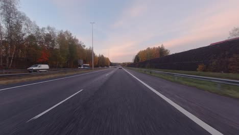Driving-POV:-Autumn-leaves-on-trees-line-highway-on-morning-commute