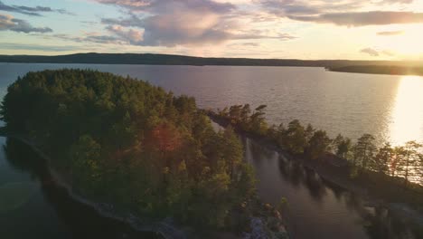 Orange-Sunset-drone-view-flying-around-small-Swedish-islands-and-a-large-lake,-4k