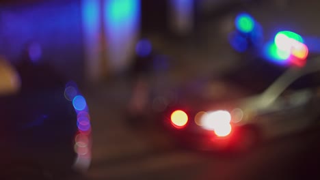 Flashing-police-car-on-street-and-policemen-around,-blurry-bokeh-night-view