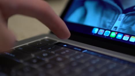Close-up-of-pro-laptop-touch-bar-strip-with-finger-pressing-video-pause-button