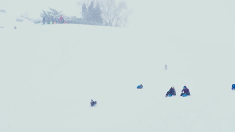 Kids-sliding-down-a-steep-snow-covered-hill-during-a-winter-storm