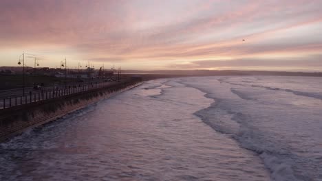 Waves-reflect-off-seawall-on-Tramore-Strand-seaside-at-dawn-sunrise