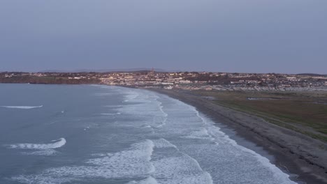 Dawn-aerial-along-Tramore-Strand-toward-seaside-coast-town-in-Ireland