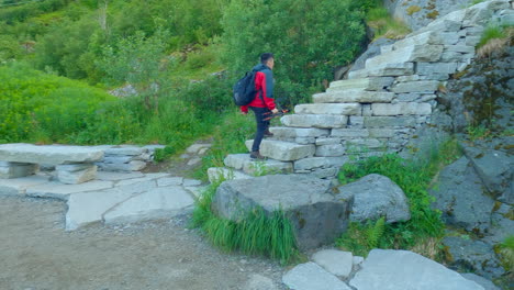 Following-shot-of-an-Asian-tourist-walking-up-the-famous-Sheppard-stairs-in-Lofoten-to-the-peak-of-Reinebringen
