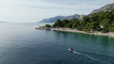 Jet-sky-moving-slowly-off-beach-Brela-Croatia-drone-aerial-medium-shot