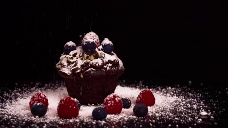 Close-up-shot-of-a-chocolate-muffin-with-red-fruits-all-around-while-powdering-white-sugar
