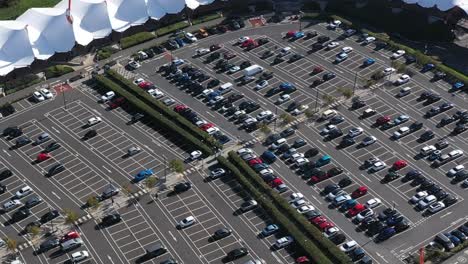 Aerial-view-tracking-a-black-car-around-a-busy-shopping-car-park