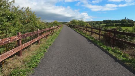 POV-ride-on-fenced-gravel-bicycle-path-in-bucolic-green-countryside