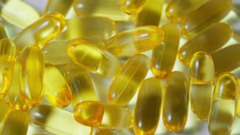 An-elderly-male-doctor-hand-picks-up-a-yellow-omega-3-pill