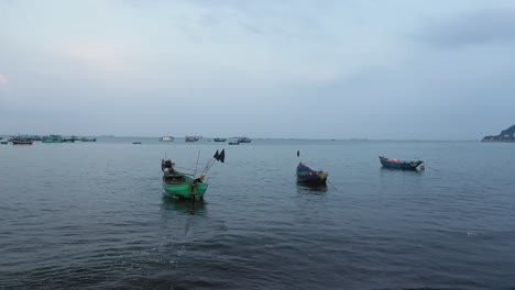 Eine-Kleine-Gruppe-Vietnamesischer-Fischerboote-Im-Seichten,-Ruhigen-Wasser-Vor-Sonnenaufgang