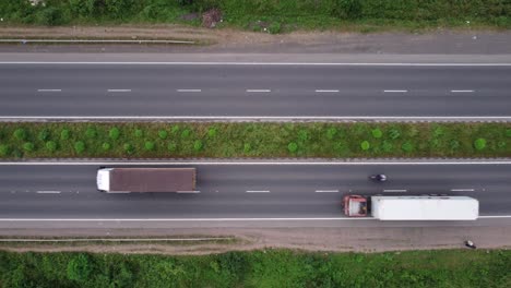 Top-down-aerial-view-of-a-four-lane-highway-in-India-with-pedestrians,-motorcycles,-passenger-cars-and-freight-trucks-passing