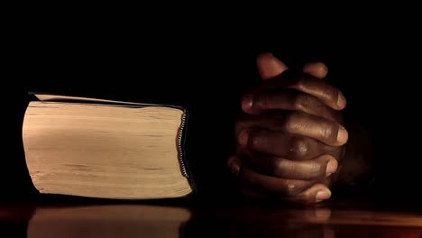 Rezando-A-Dios-Con-Las-Manos-Junto-Con-El-Hombre-Caribeño-De-La-Biblia-Rezando-Con-Fondo-Negro-Almacen-De-Video