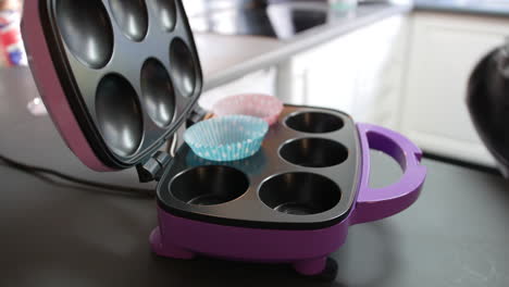 A-girl-placing-paper-cupcake-liner-cases-in-a-baking-machine