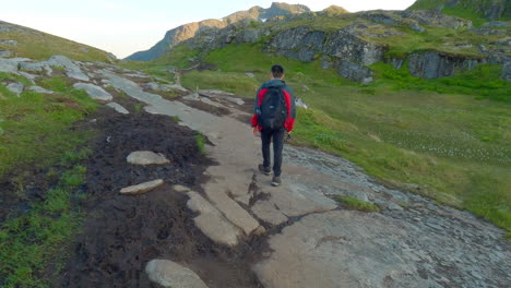 Asian-male-walking-in-the-mountains-on-Lofoten-Island-in-Northern-Norway-on-a-nice-sunny-day,-Following-Shot