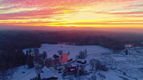 Vibrant-fire-sky-sunset-over-Europe-winter-landscape-with-lake-and-snow,-drone-view