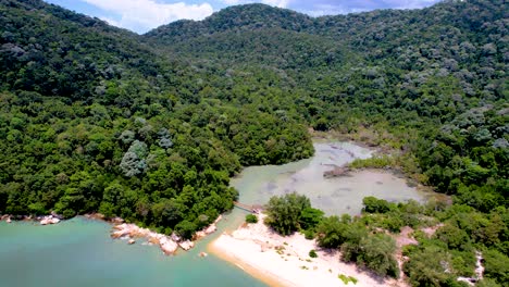 Aerial-drone-rotating-shot-over-Meromictic-lake-surrounded-by-lush-green-vegetation-in-Penang-National-Park,-Penang,-Malaysia-at-daytime