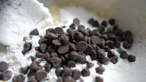 Close-up-of-chocolate-chips-being-added-to-cookie-dough-cake-mix-with-flour-butter-and-sugar