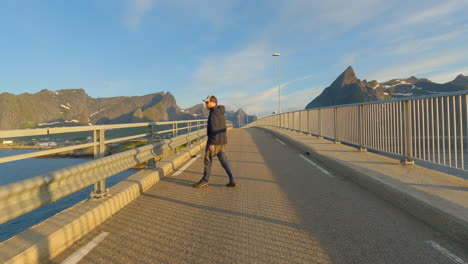 Junger-Mann-Genießt-Die-Aussicht-Während-Der-Mitternachtssonne-Auf-Der-Hamnoy-Brücke,-Insel-Lofoten,-Norwegen