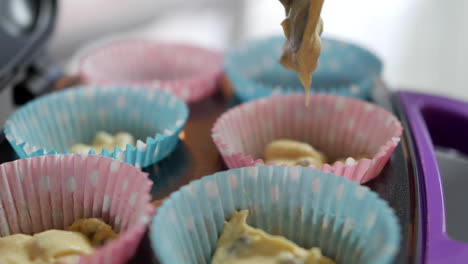 Close-up-of-adding-cake-mixture-to-paper-cupcake-baking-tray