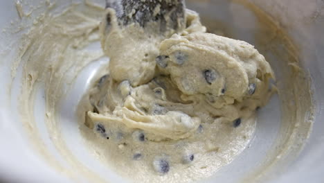 Mixing-chocolate-chip-cookie-dough-cake-mixture-in-a-bowl-with-a-wooden-spoon