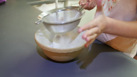 A-girl-sieving-flour-into-a-bowl-for-baking