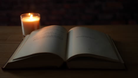 Pages-of-an-old-antique-book-turning-in-the-wind-next-to-a-candle-in-a-dark-room
