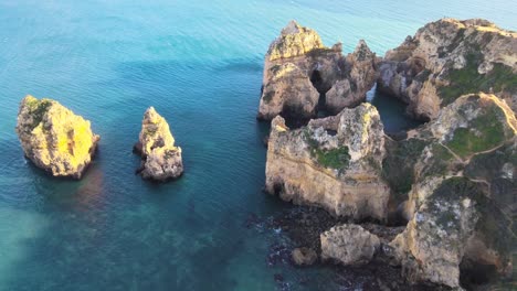 flying-above-clear-blue-water-amongst-natural-archway-and-tower-rock-formations