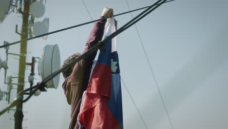 Ein-Junger-Mann-Befestigt-Eine-Slowenische-Flagge-An-Einem-Kabel-In-Der-Nähe-Eines-Funkturms-Auf-Dem-Berg-Mrzlica