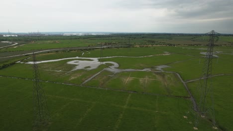 Rising-aerial-view-over-electric-distribution-pylon-towers-on-flooded-countryside-field