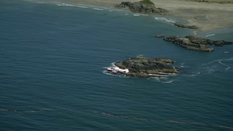 High-Angle-Shot-of-Small-Airplane-Flying-over-a-Rocky-Coastline