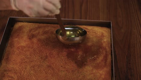 Pastry-chef-pouring-the-syrup-over-the-dessert-pan-with-cooking-spoon