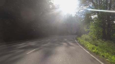 Drive-POV:-Rounding-bend-in-country-highway-into-direct-sunlight