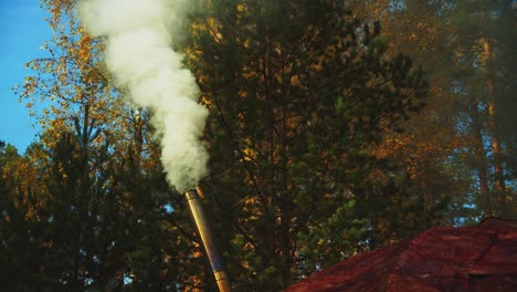Boreal-forest-camp-wood-stove-chimney-smokes-at-autumn-camping-site