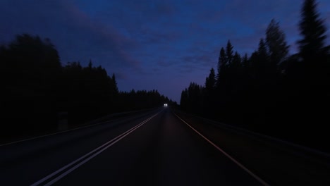 POV-highway-driving,-oncoming-car-headlights-during-blue-hour-dawn