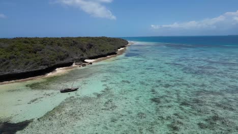 Sailboat-floating-above-the-shallow-coral-lagoon-in-Pungume-Island-Tanzania-Africa-southern-Zanzibar,-Aerial-right-rising-shot