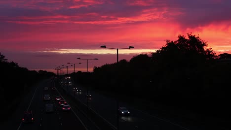 Early-morning-highway-traffic,-with-a-colourful-sunrise-in-the-background