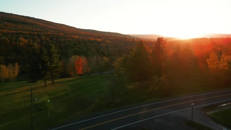 Light-flare-of-sunset-as-drone-flies-over-road---The-Catskills,-Upstate-New-York