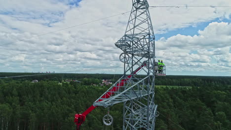Drone-rotation-around-high-voltage-electricity-tower-and-technicians-in-their-uniform-inspecting-technicalities-using-lifting-crane