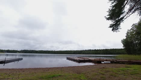 Quiet-forest-lake-docks-as-overcast-cloud-drifts-slowly-overhead