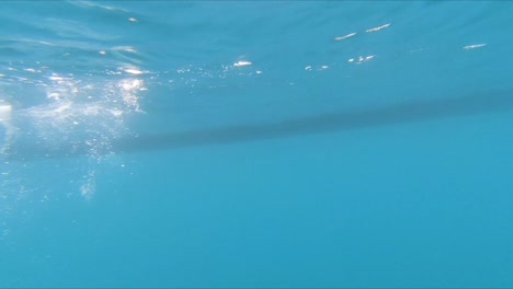 Underwater-point-of-view-of-rowing-boat-paddles-breaking-through-the-surface