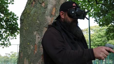 Bearded-male-wearing-wireless-FPV-goggles-controlling-drone-in-park-with-motion-joystick