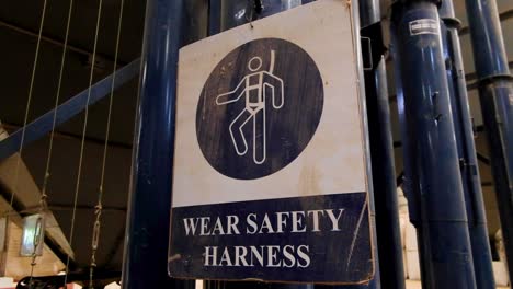 Caution-health-and-safety-sign-with-wear-safety-harness-and-graphic-of-person-climbing-with-correct-personal-protective-equipment-PPE-in-the-workplace