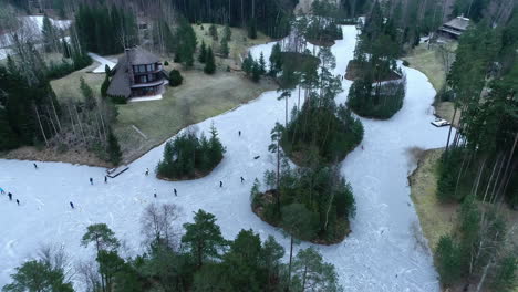 People-Ice-skating-frozen-lake-in-Europe,-drone-view