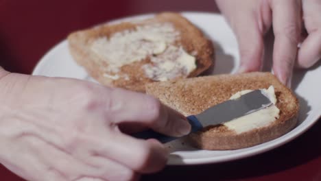 caucasian-hands-smearing-butter-on-toast-lying-on-a-plate-in-close-up-and-slow-motion