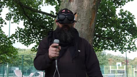 Bearded-male-wearing-FPV-goggles-controlling-drone-in-park-with-movement-joystick