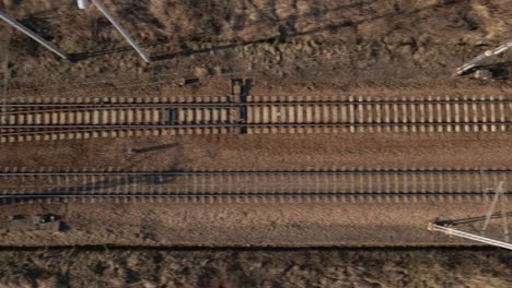 Birds-eye-view-of-railway-during-the-sunset-and-golden-hour,-moving-sideways---drone-footage