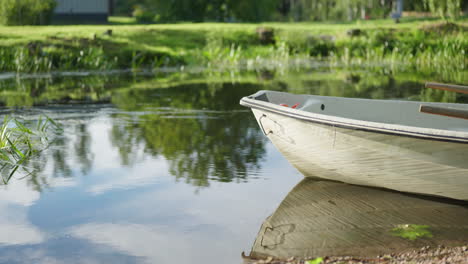 Ein-Ruderboot-Auf-Einem-Ruhigen-Fluss-Mit-Wasser,-Das-Sich-An-Einem-Sonnigen-Sommertag-Langsam-Bewegt