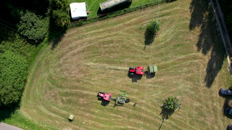 Aerial-view-looking-down-at-pair-of-tractors-harvesting-agricultural-grassland-field