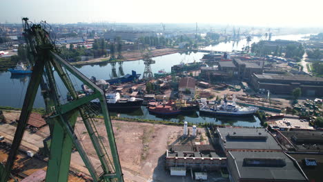 Aerial-view-passing-large-green-port-cranes-to-reveal-Gdansk-shipyard,-Poland