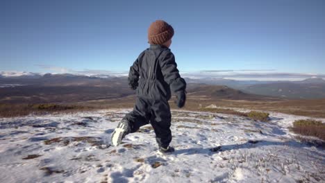Rear-view-of-child-running-down-mountain-late-autumn-and-crisp-air-with-spectacular-views